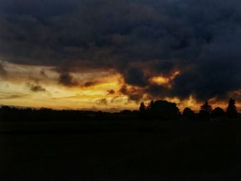 Silhouette landscape against dramatic sky during sunset