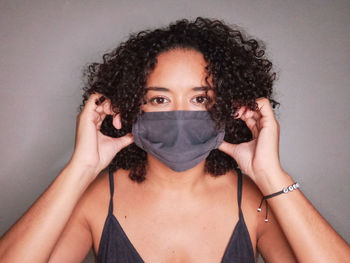 Portrait of woman covering face against wall