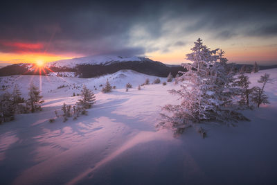 Scenic view of snow covered landscape against sky during sunset