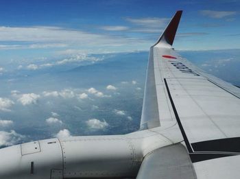 Cropped image of airplane flying over cloudscape against sky