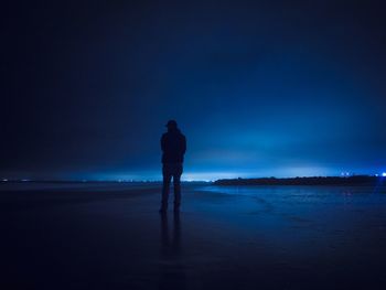 Woman standing at sea against sky at night