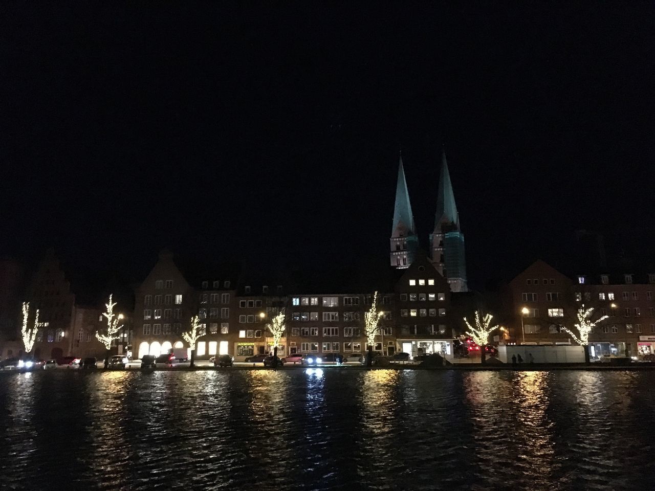 ILLUMINATED CITY BY RIVER AGAINST SKY