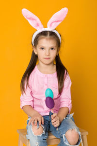 Portrait of cute girl holding toy against yellow background