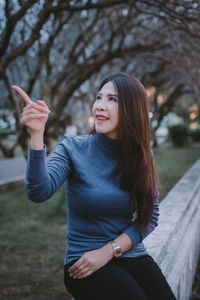 Portrait of smiling young woman against trees