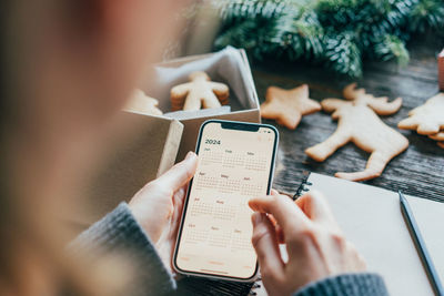 Close-up of a woman holding a phone with a calendar on the screen.