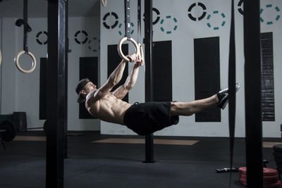 Full length of shirtless man exercising at gym