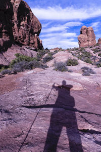 Shadow of person on rock against sky