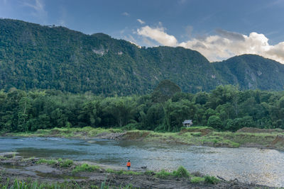 Scenic view of river by mountains against sky