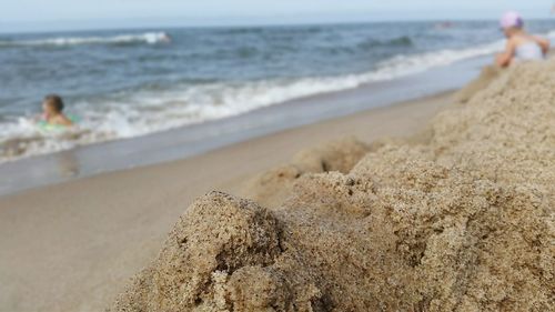 Midsection of woman on beach against sky