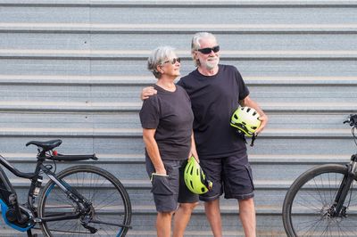 Couple with bicycles against corrugated iron