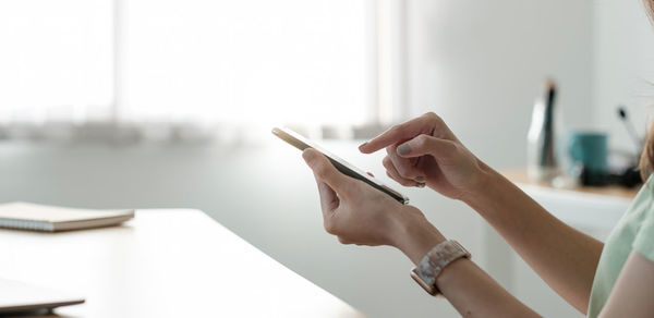 Midsection of man using smart phone on table