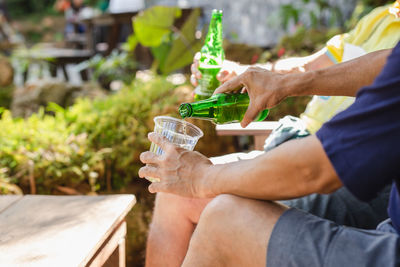 Man pouring beer in plastic glass from bottle during vacation.