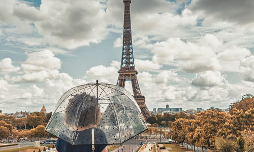 Rear view of woman holding umbrella standing against eiffel tower