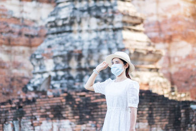 Midsection of woman holding smart phone while standing against buildings