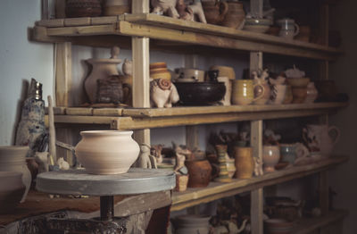 Clay pot close-up on potter's wheel. inside interior. wooden racks in pottery workshop in 