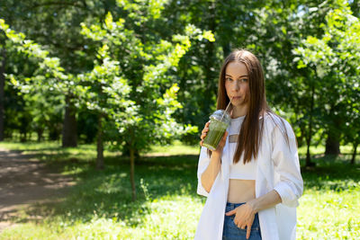 Young woman standing against plants