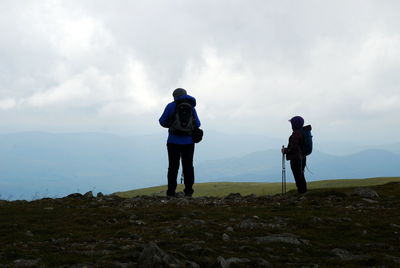 Rear view of man photographing on landscape against sky