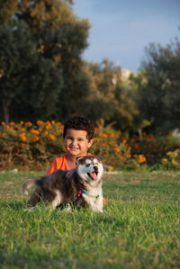 Portrait of smiling young boy with dog on grass