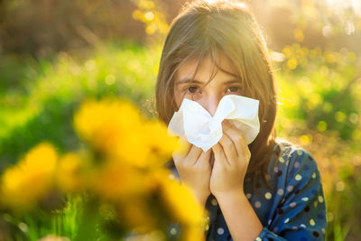 Portrait of girl blowing nose with tissue