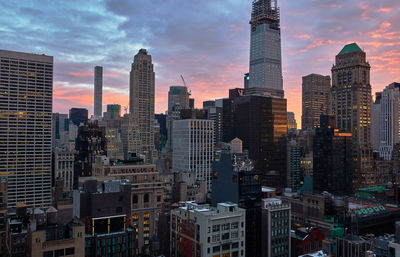 Modern buildings in city against sky during sunrise