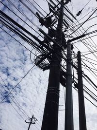 Low angle view of electricity pylon against cloudy sky