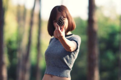 Midsection of woman standing by tree trunk in forest