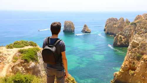 Rear view of man looking at sea against sky