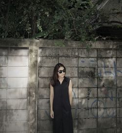 Portrait of young woman standing against wall