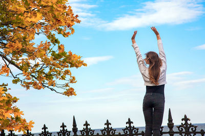 Woman standing by tree against sky