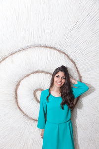 Portrait of smiling young woman standing against wall