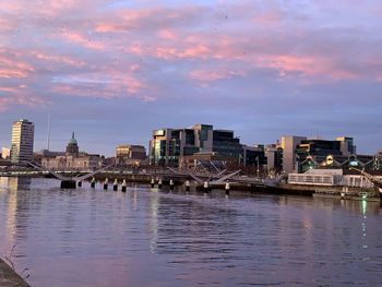 View of buildings at waterfront against cloudy sky