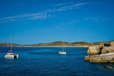 Sailboats sailing in sea against blue sky