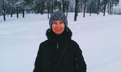 Portrait of smiling woman standing on snow covered field