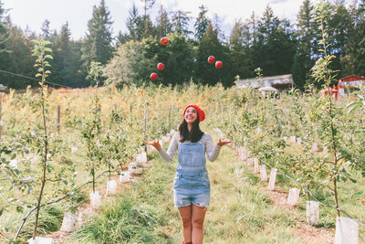 Young woman throwing apples on field