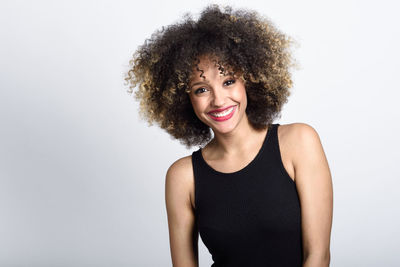 Portrait of smiling young woman with curly hair against white background