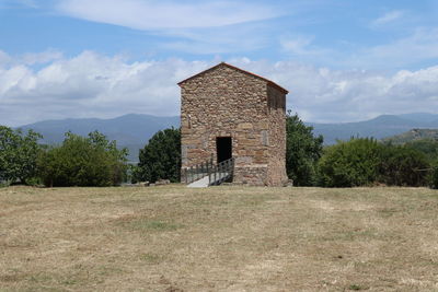 Old house on field against sky