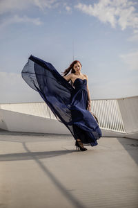 Young woman wearing blue dress standing on building terrace