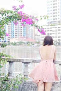 Rear view of woman standing against lake in city