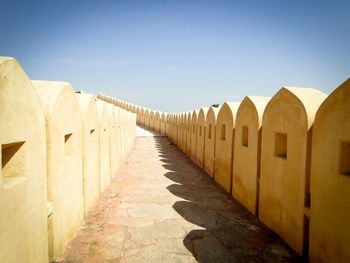 Walkway amidst retaining walls against sky