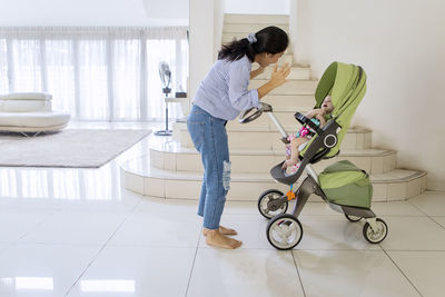 Side view of woman with baby in carriage on tiled floor