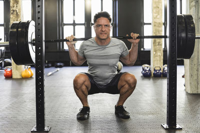 Smiling man exercising with dumbbells in gym