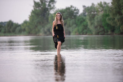 Portrait of young woman standing by lake