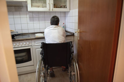 A disabled woman in a wheelchair washes dirty dishes