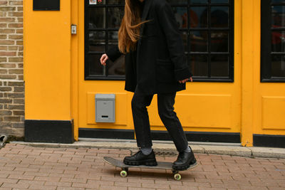 Girl near yellow wall with a skateboard