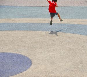 Rear view of boy jumping at playground during sunny day