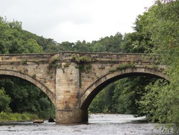 Arch bridge over river against sky