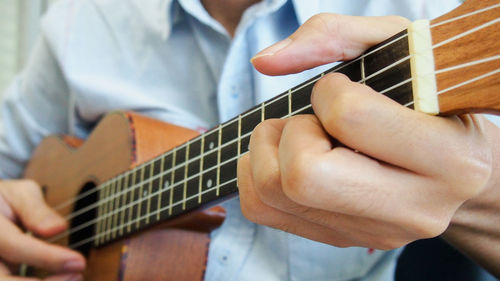 Midsection of man playing guitar