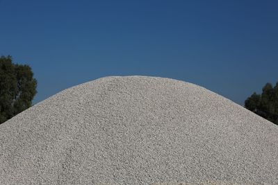 Low angle view of stone wall against clear blue sky