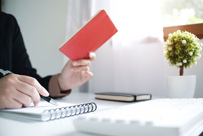 Midsection of businessman writing in book at desk