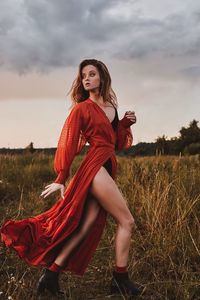 Young woman standing on field against sky